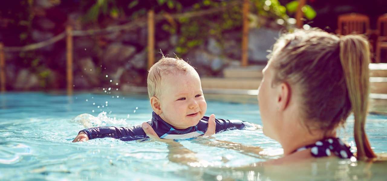 A mother on holiday with her infant in the pool.