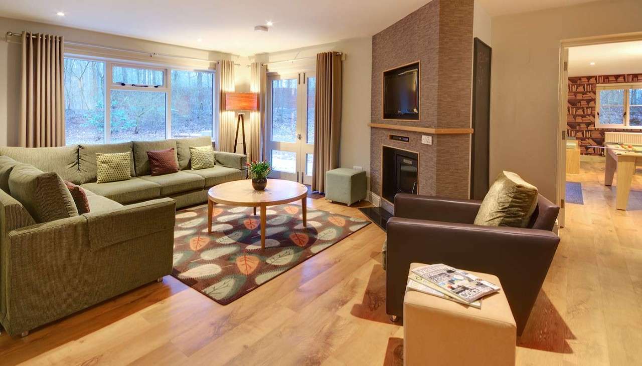 The living area of a 4 bedroom Exclusive lodge, in the foreground is a large L shaped corner sofa, armchair and coffee table.