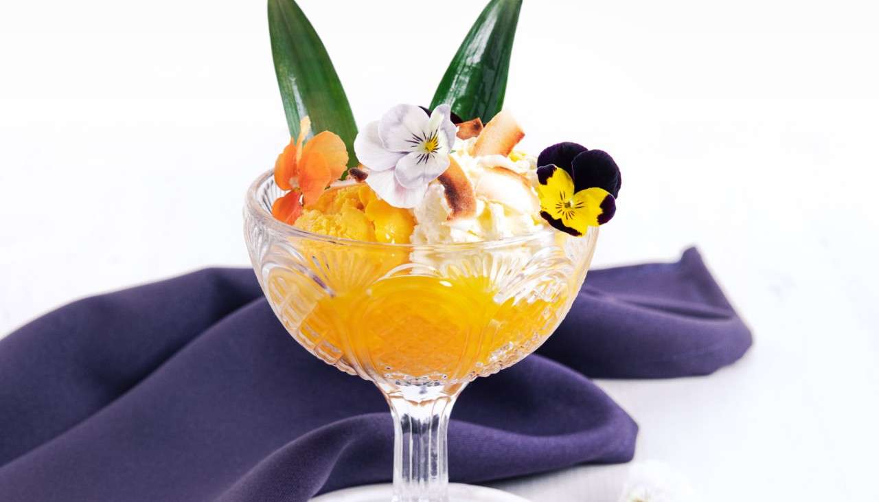 Fresh drinks topped with edible flowers and fresh fruit.