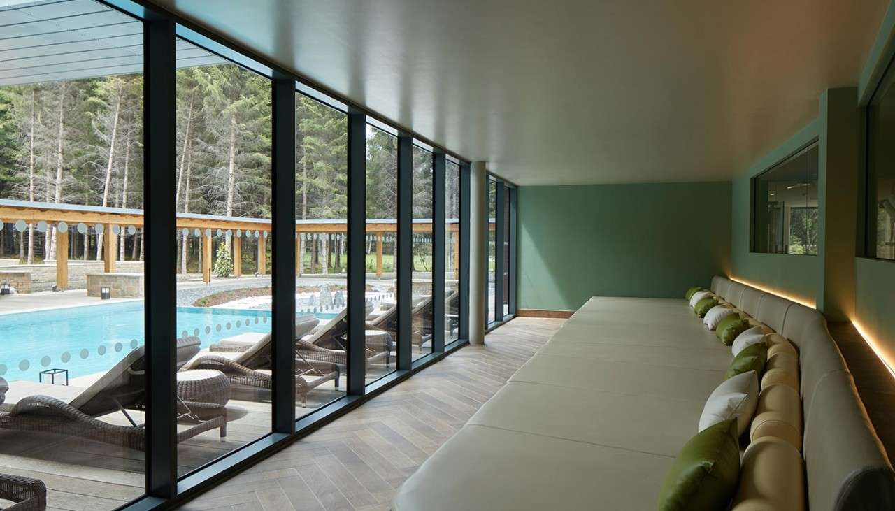 Comfortable bed with views out to the Outdoor Pool and surrounding forest.