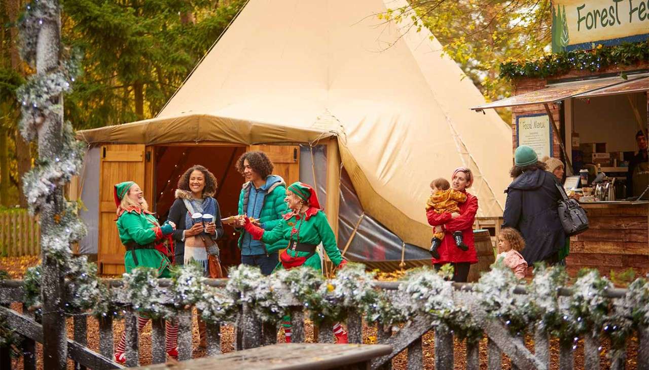 People and elves holding hot drinks outside a tipi.