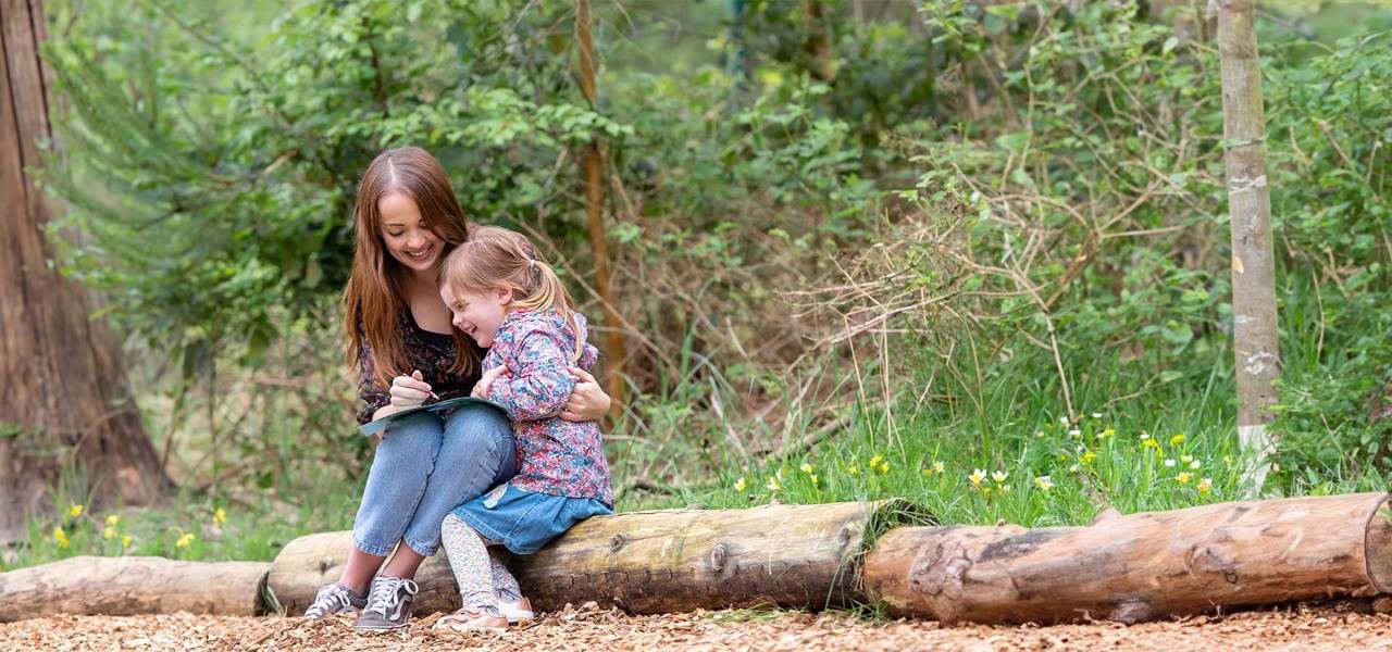 A little girl and her mum doing an easter egg hunt in the forest.