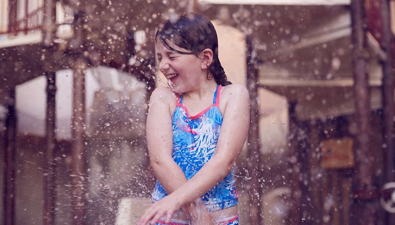 Girl splashing in water play area at the Subtropical Swimming Paradise