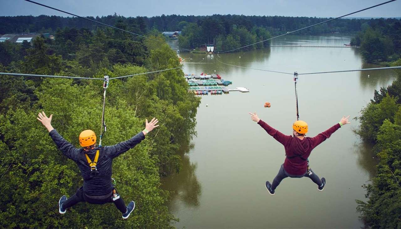 View from behind of two people going down the zip wire over the lake on Aerial Adventure