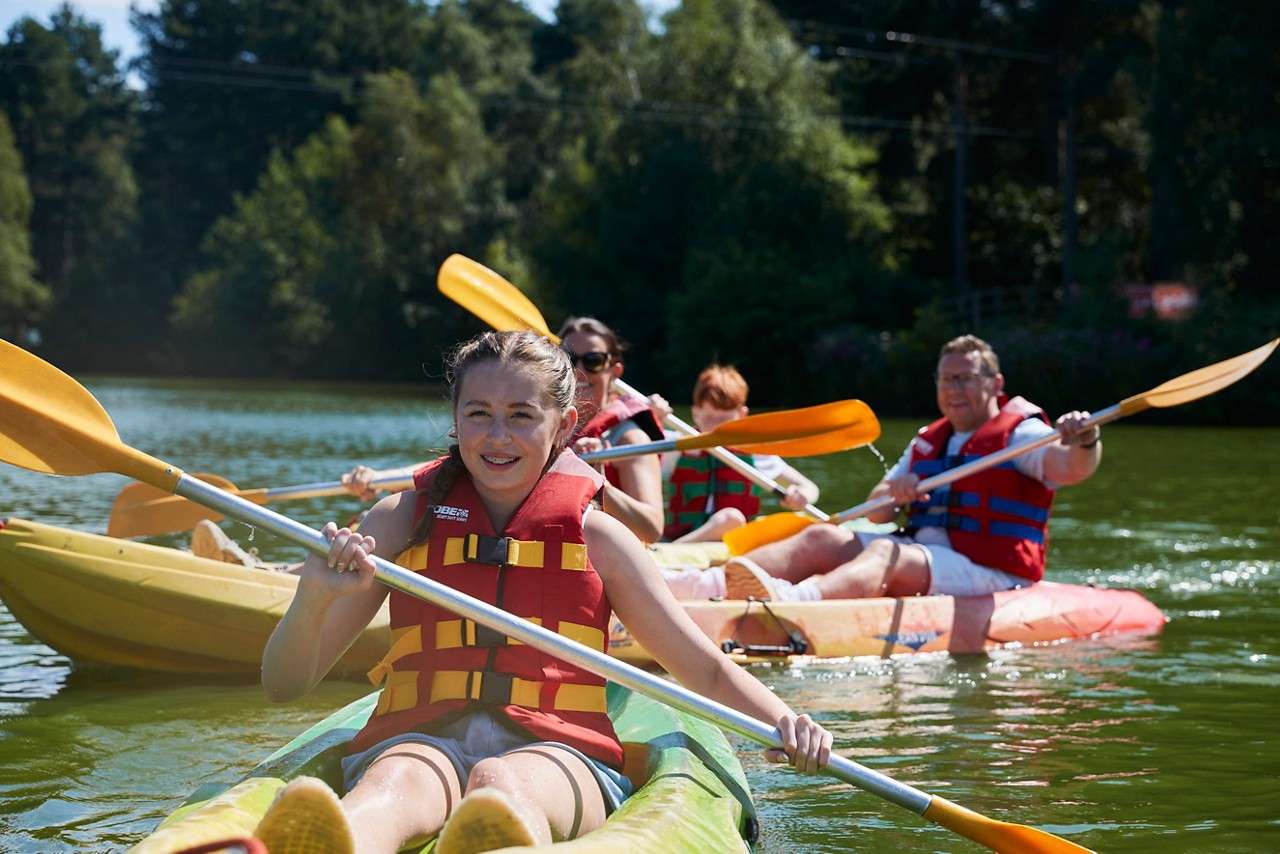 A brother and sister holding hands whilst splashing their feet in the water at the beach.