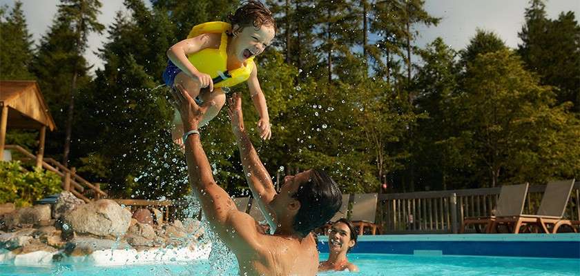 A father throwing his young child in the air in a swimming pool