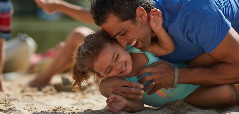 Father and daughter play together on a beach