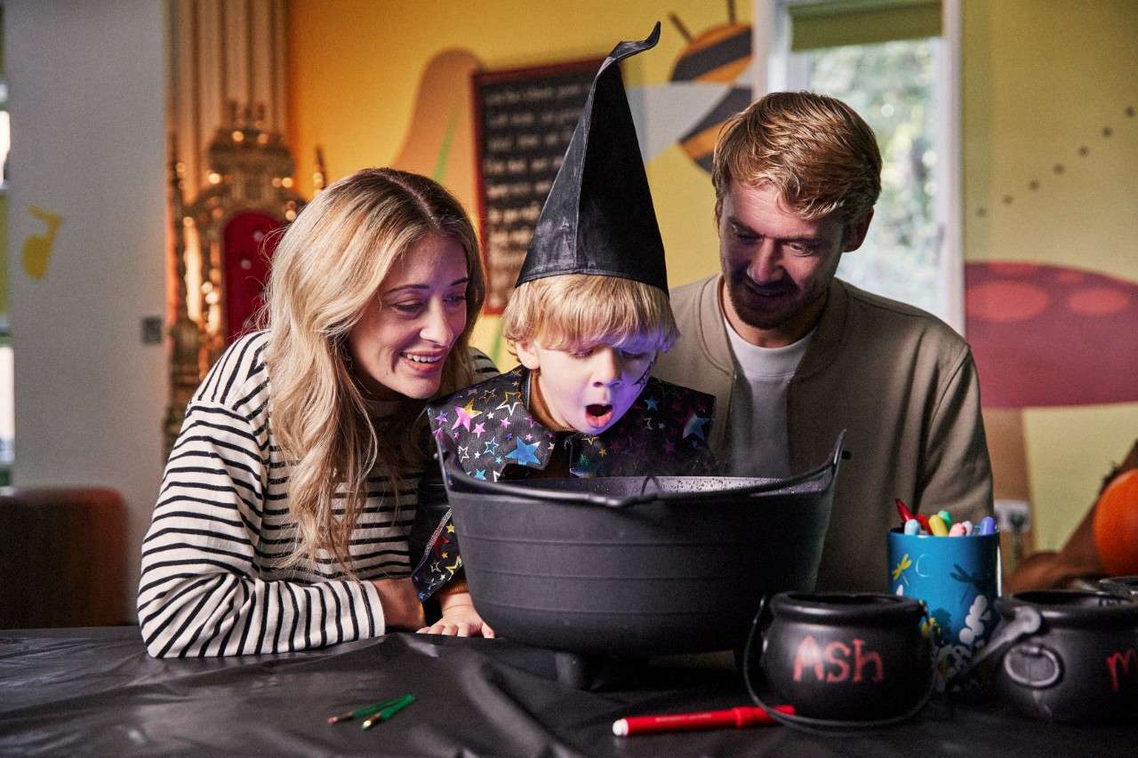 Family with young child dressed as a wizard looking into a cauldron in the Activity Den