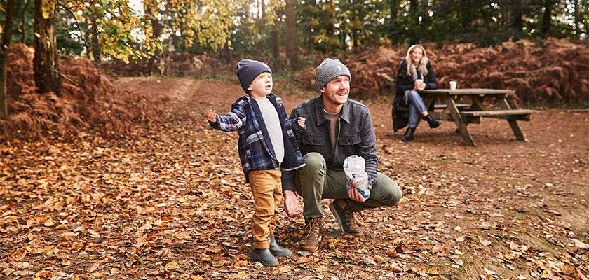 A father crouched down to his sun amongst the golden autumn leaves