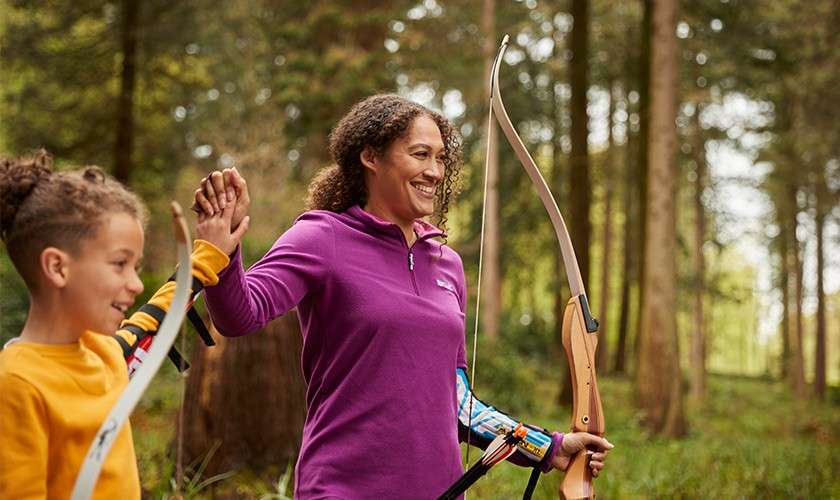 A brother and sister giving each other a high-five whilst doing Archery.