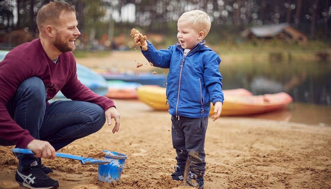 Father and sun playing with a spade in the sand on the beach