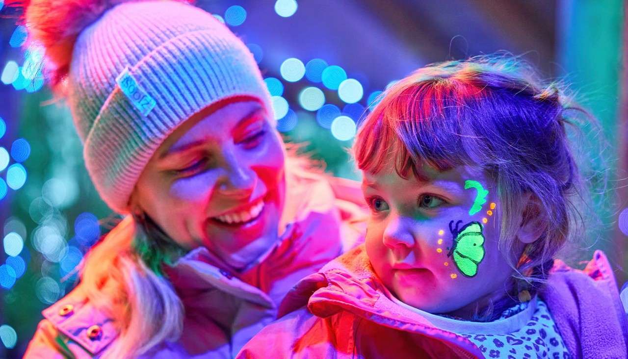A mother looking at her child with glow in the dark face paint on.