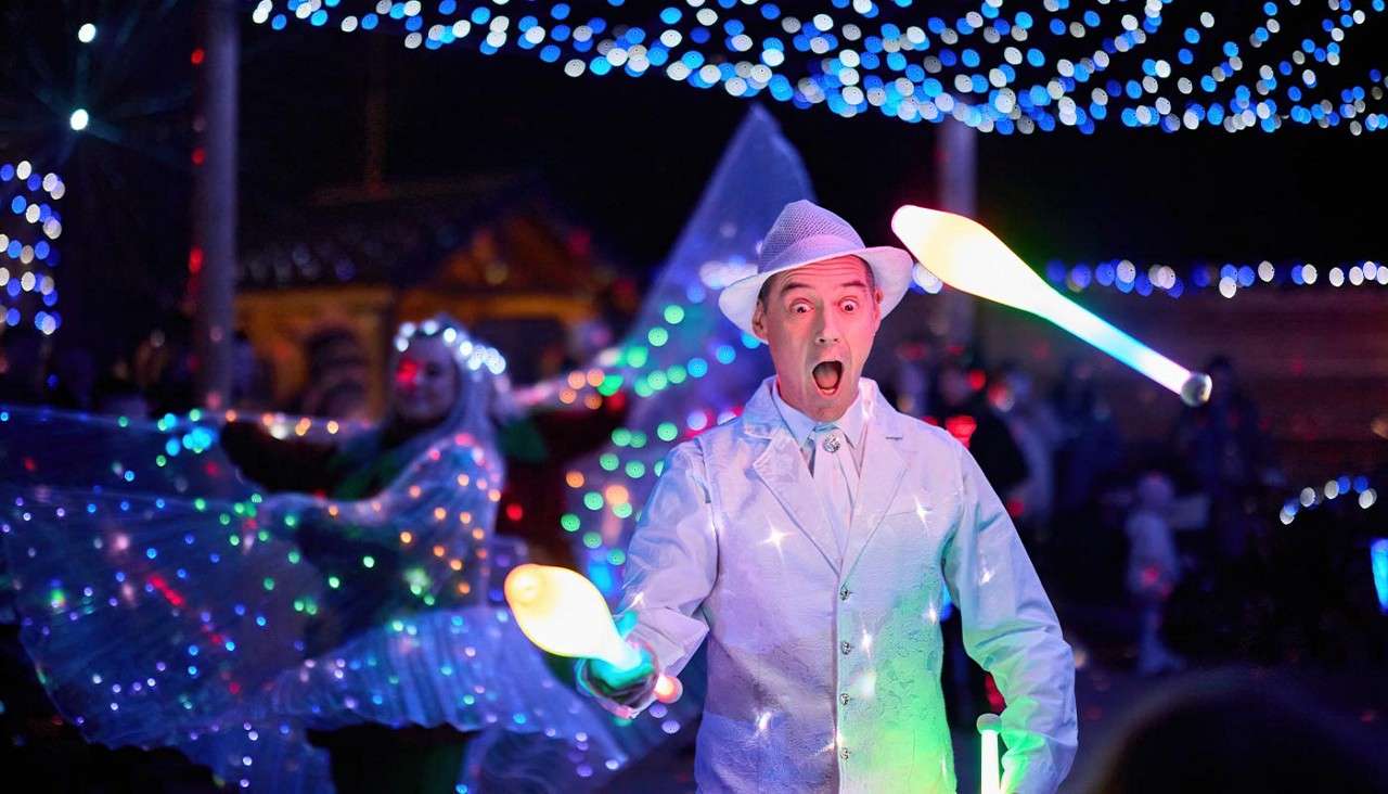 A man juggling glow in the dark juggling pins.