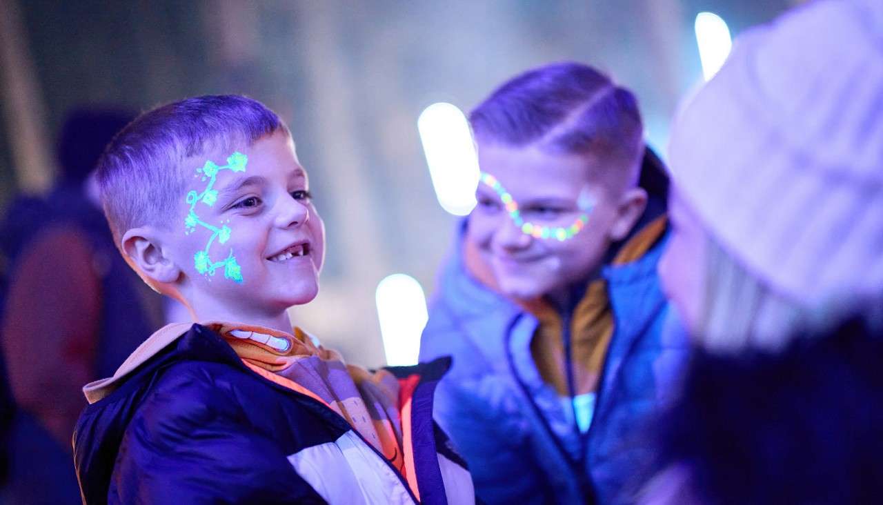 Two young boys with glow in the dark face paint on their face.