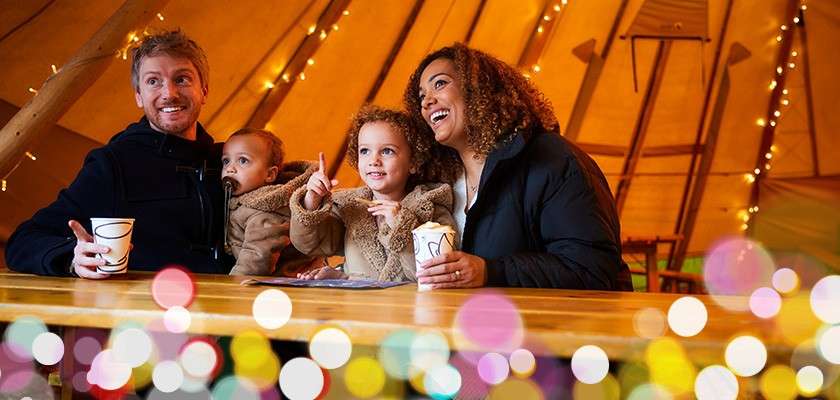 A family sat in the Tipi with hot chocolates.