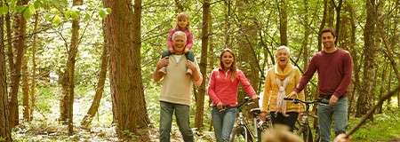 A family including grandparents walking through the forest together.