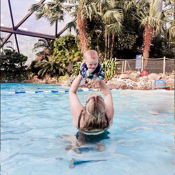 A woman playing with her baby in a swimming pool.