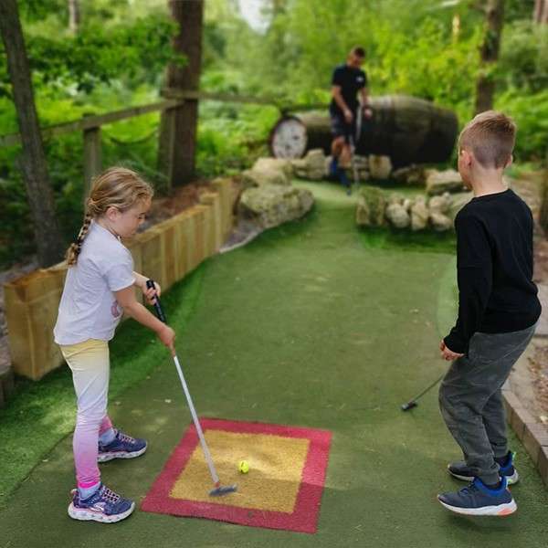 Two children playing mini golf together.