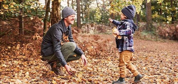 A father and son playing amongst the autumnal leaves.