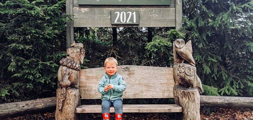 A toddler sat on a bench underneath a sign that says "2021".