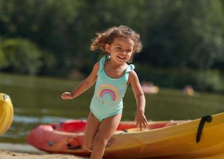 A toddler running on the beach.