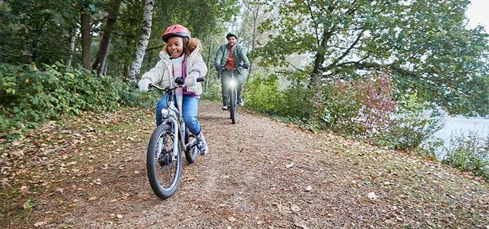 A family cycling through the autumn forest.