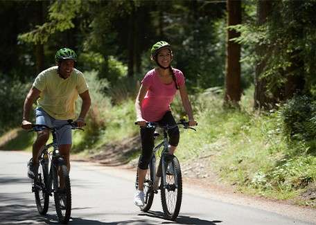 A couple cycle through the forest