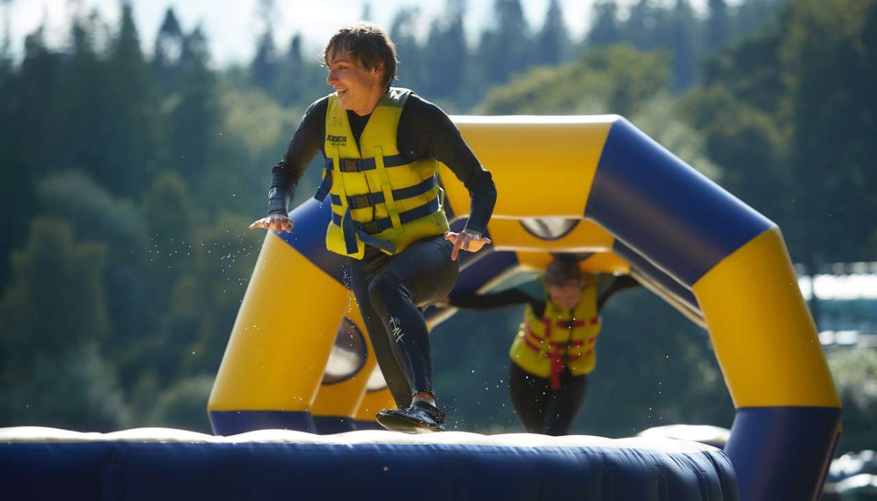 Young person running across an inflatable obstacle course floating on the lake