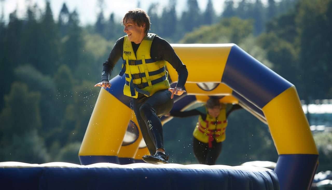 Young person running across an inflatable obstacle course floating on the lake
