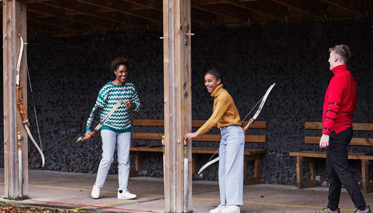 A mum and daughter laugh as they play archery