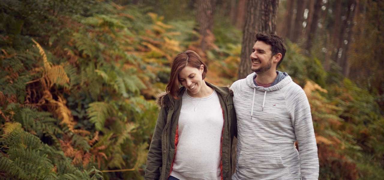 Pregnant couple walking through forest