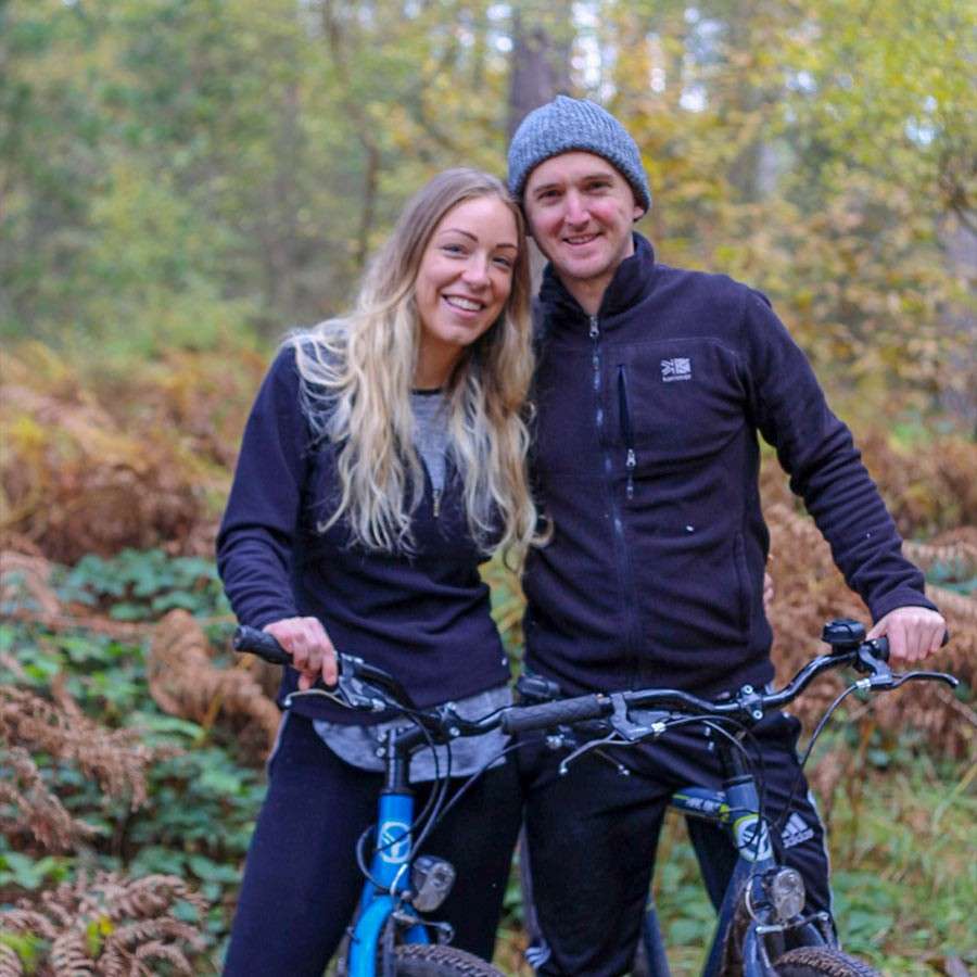 Man and woman smiling for a photo while sat on cycles.