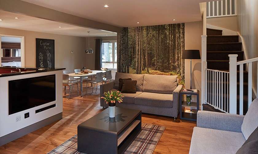 An Executive Lodge ;iving area with sofa, tv and dining table in view. 