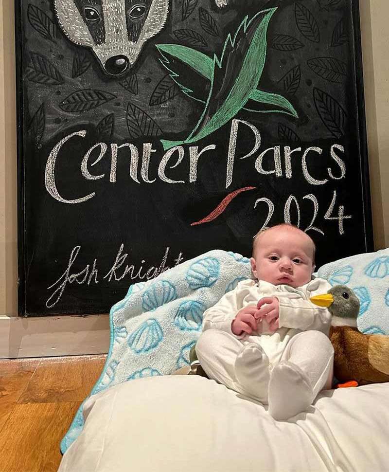 A baby in front of a Center Parcs chalk board