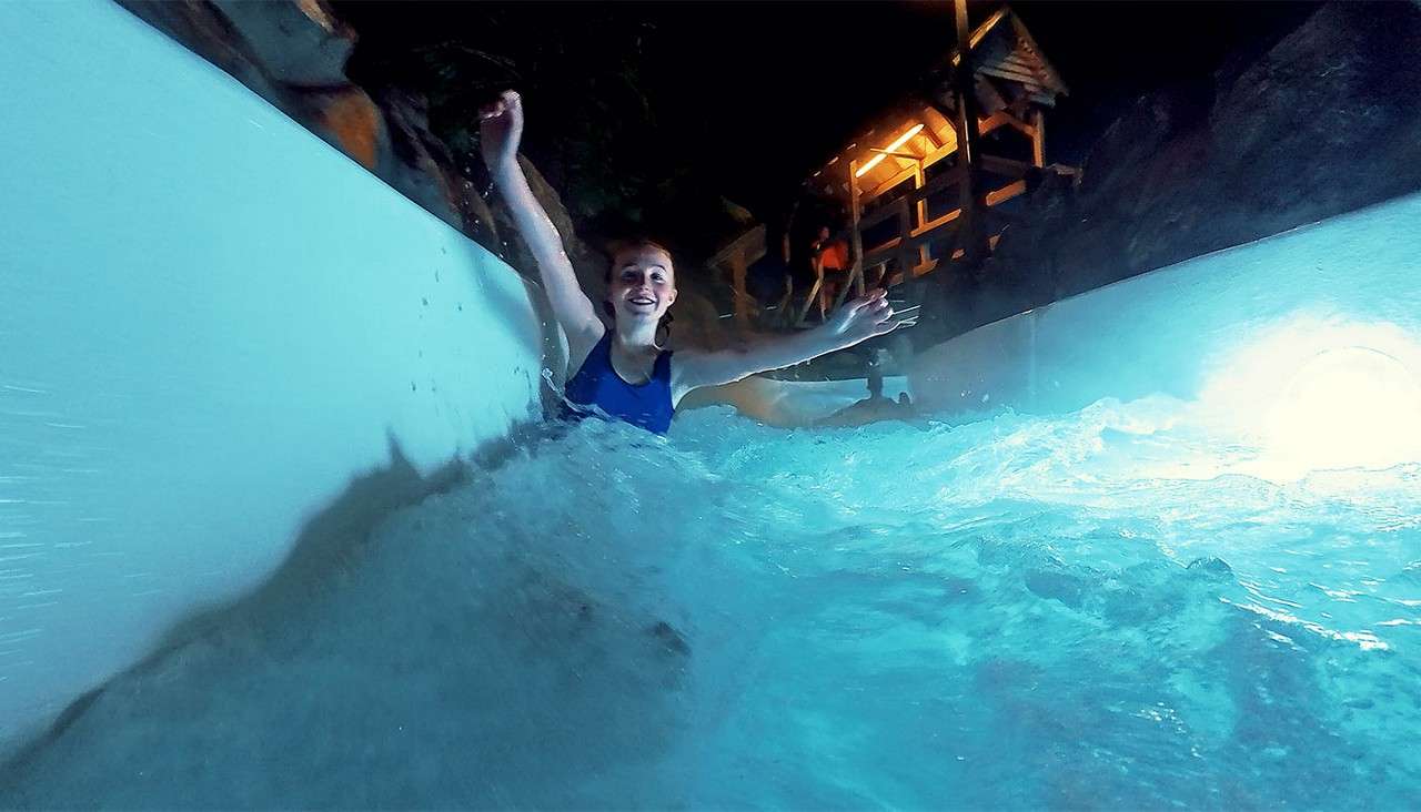A girl going down the Wild Water Rapids at night.
