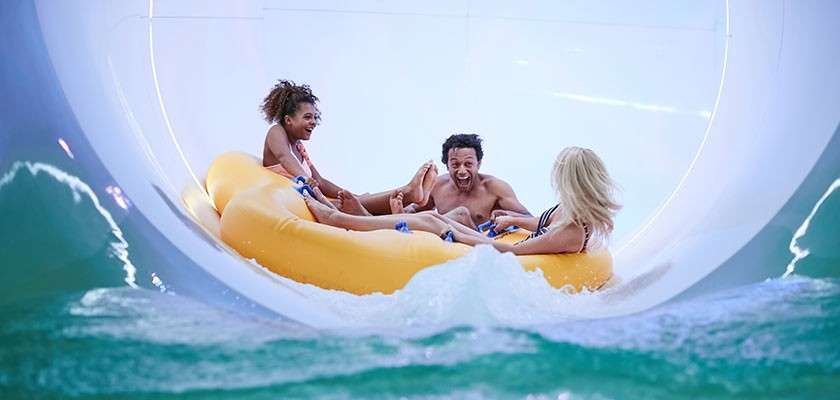 A family going down the water slides in an inflatable.