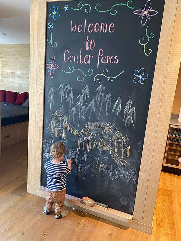A child drawing on a chalkboard which says 'Welcome to Center Parcs'.