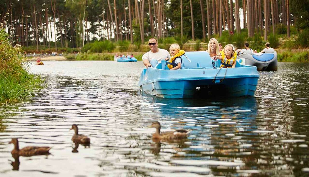Family on a pedalo on the lake, ducks can be seen swimming beside them