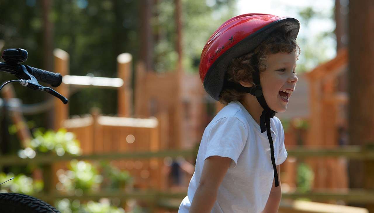 A boy wearing a bike helmet in the forest 