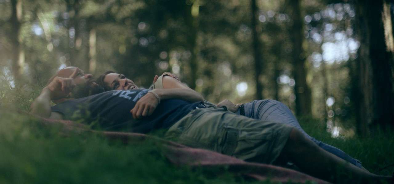 Couple laying in forest looking up to the sky