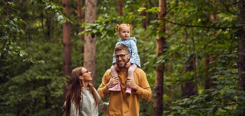 Family walking through forest with child on fathers shoulders