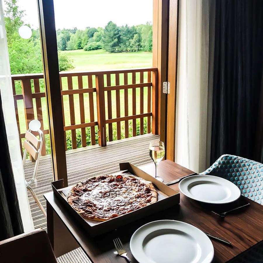 Table set up with pizza and wine in a Center Parcs apartment, showing a beautiful forest view from the balcony