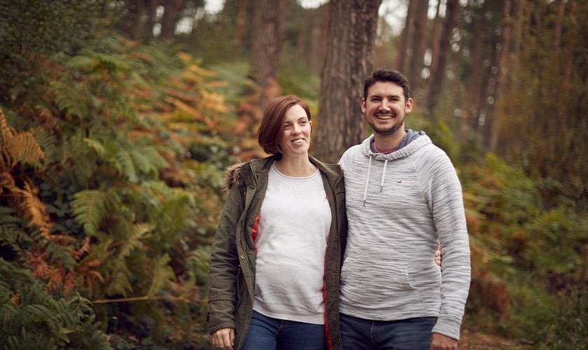 Man and pregnant partner walking through the forest