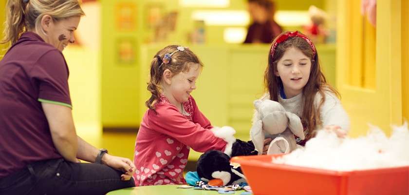 Two young girls play in the activity den making teddy bears with a Center Parcs staff member