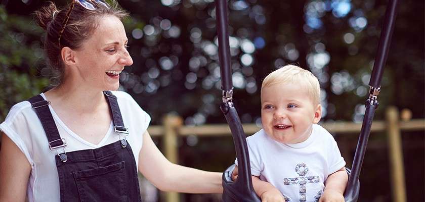 Mother pushing child in a swing