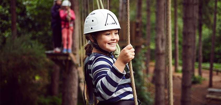 Girl on Aerial Adventure crossing bridge in the tree top