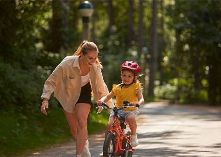Woman helping a young girl balance on her bike.
