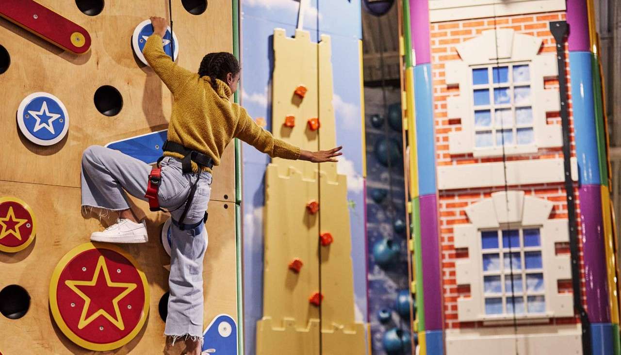 Girl scaling a colourful climbing wall.