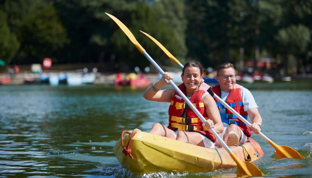 Two people sitting in a Double Kayak on the lake.