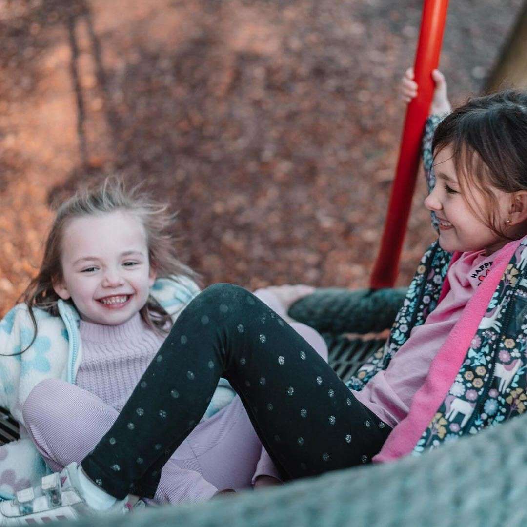 Two girls laughing on a swing